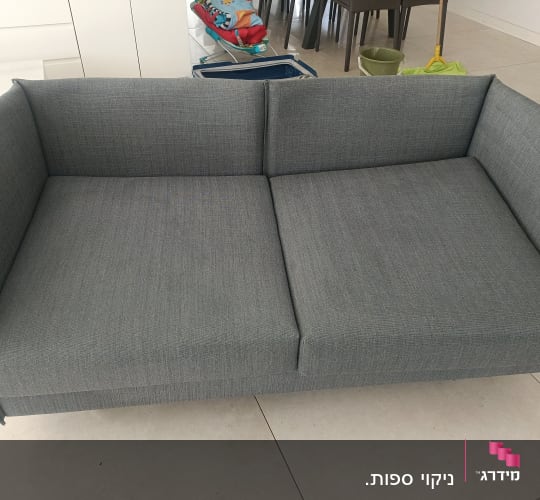 ספה אפורה עם כלי ניקוי ברקע